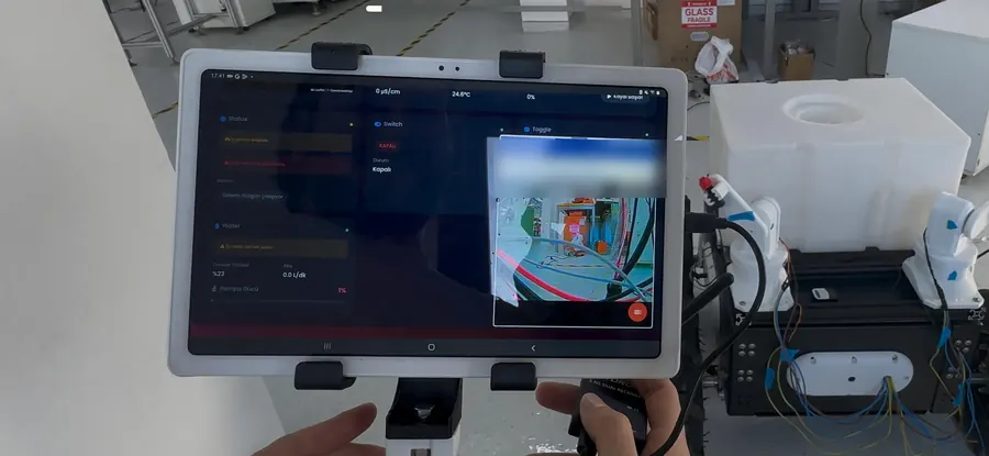 Kumandaya bağlı Android tablette robotun canlı kamera görüntüsü ve sensör verileri, arkada robot